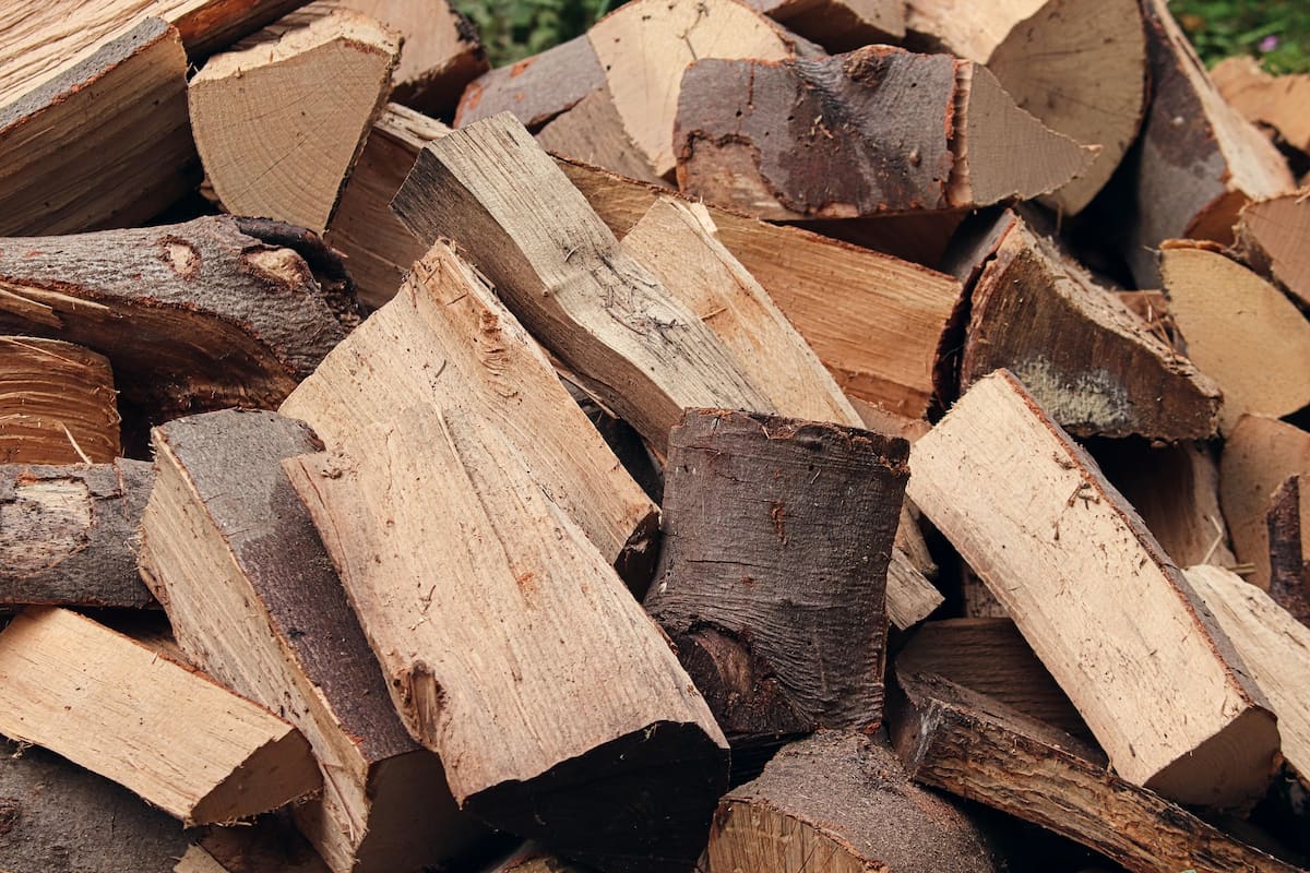 Split oak firewood stacked in a crisscross pattern, showing the characteristic grain and bark of red oak